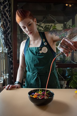Edibles maker Rachel Leavy pours an infused vinaigrette dressing over a spring salad. Leavy also creates edibles that help friends with everything from chronic pain to side effects from cancer treatments. - PHOTO BY JACOB WALSH