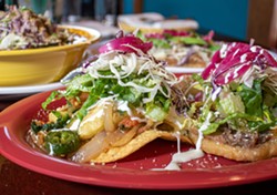 Closeup photo of tacos on a red plate.